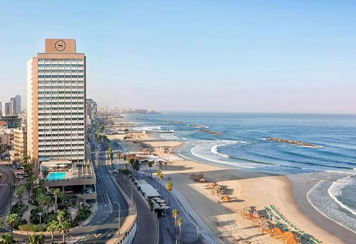 Gay-friendly Sheraton Tel Aviv Hotel, a pet-friendly beachfront property. View of the hotel tower, beach, and Mediterranean Sea. Tel Aviv gay travel.