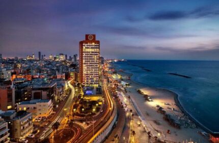 Night view of the gay-friendly Sheraton Tel Aviv Hotel. Beachfront property, pet-friendly, city lights, and Mediterranean Sea.