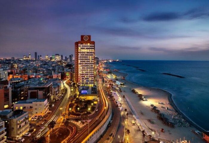 Night view of the gay-friendly Sheraton Tel Aviv Hotel. Beachfront property, pet-friendly, city lights, and Mediterranean Sea.