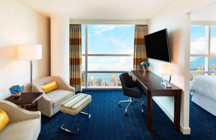 Sheraton Vancouver Wall Centre gay-friendly hotel room. Seating area, desk, TV, and a view of the city. Modern design, comfortable stay.