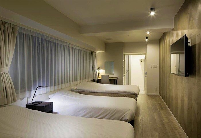Shinjuku City Hotel N.U.T.S Tokyo, gay-friendly hotel room. Three beds, desk, TV, and bathroom. Modern design, comfortable for gay travelers.