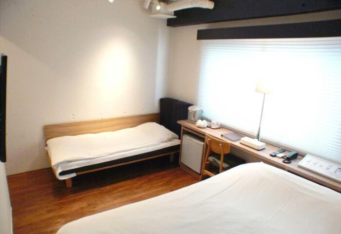 Shinjuku City Hotel N.U.T.S Tokyo room. Gay-friendly hotel with beds, desk, chair, and window. Modern design for gay travelers in Tokyo.