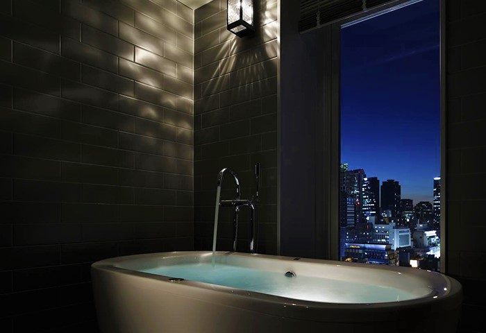 Hotel bathroom at the gay-friendly Shinjuku Granbell Hotel. Bathtub with a city view at night. Luxury travel in Tokyo, Japan.