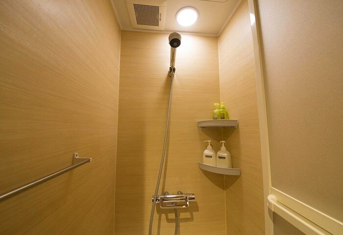 Shower at Shinjuku Kuyakusho-mae Capsule Hotel, a gay-friendly hotel. Features toiletries, towel bar, and clean design for gay men travelers.