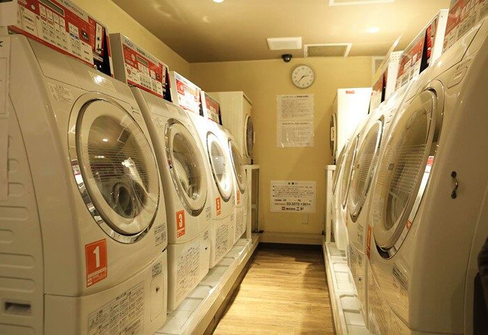 Laundry room at Shinjuku Kuyakusho-mae Capsule Hotel. Gay-friendly hotel with coin-operated washing machines for guests' convenience.