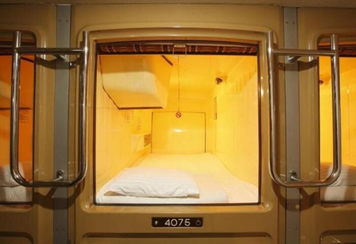 Interior of a capsule at Shinjuku Kuyakusho-mae Capsule Hotel, a gay-friendly hotel in Tokyo, Japan. Sleeping pod with bed and ladder.