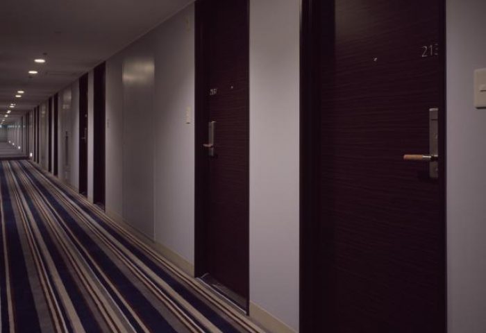 Hallway view at Shinjuku Prince Hotel, a gay-friendly hotel. The corridor has dark wood doors and a striped carpet, offering a quiet, safe space.
