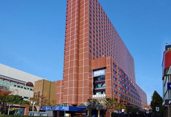 Shinjuku Prince Hotel, a gay-friendly hotel in Tokyo. The building is tall and modern, with a red brick facade and many windows. Pepe sign visible.