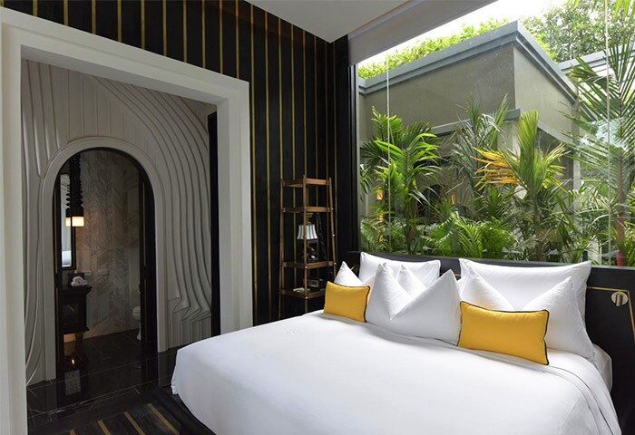 Shinta Mani Angkor's gay-friendly hotel pool villa. Modern bedroom with a view of lush greenery. Luxury travel for gay men in Cambodia.