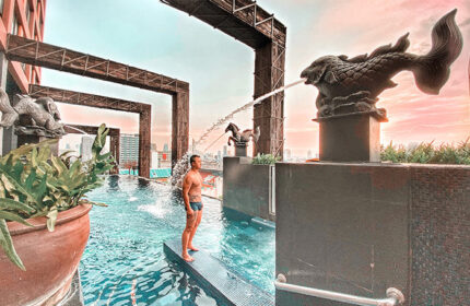 Siam @ Siam Design Hotel Bangkok pool view. Gay-friendly hotel with man in swimwear. Fish and horse statues with water feature.