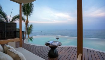 Silavadee Pool Spa Resort's gay-friendly hotel view. Infinity pool, wine, and ocean vista from a luxurious suite. Perfect gay travel destination.