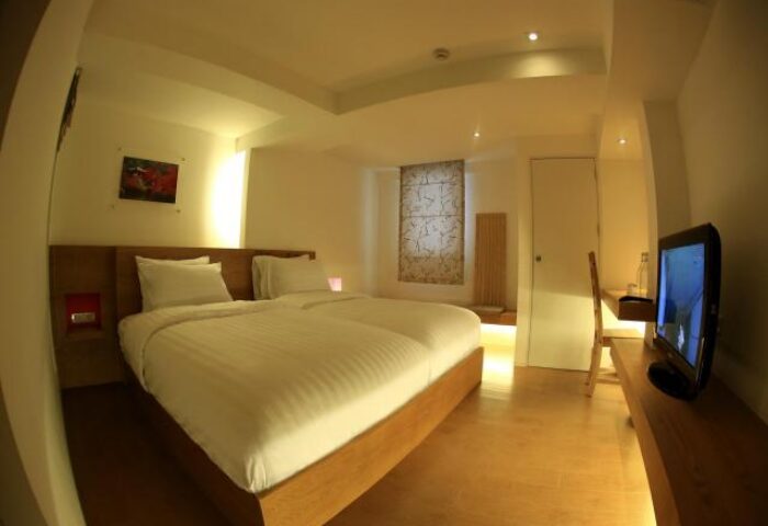 Silom One Hotel room. Gay-friendly hotel in Bangkok, Thailand. Bedroom with double bed, TV, desk, and modern decor. Ideal accommodation for gay travelers.