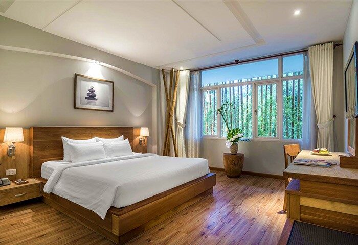 Silverland Yen Hotel room. Gay-friendly hotel with wooden bed frame, desk, and large window. Modern design, bright, and comfortable.