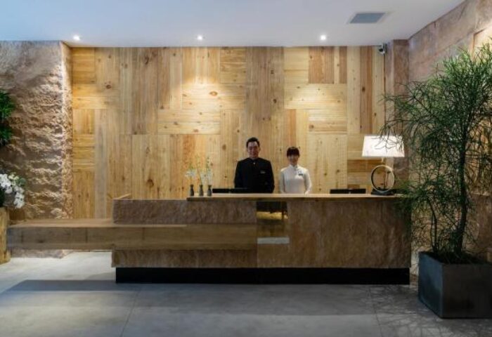 Silverland Yen Hotel's front desk. Staff at reception. Gay-friendly hotel with wood paneling and plants. Modern design.