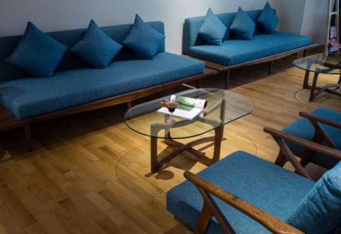 Silverland Yen Hotel lounge area. Modern blue sofas, chairs, glass table, wood floor. Gay-friendly hotel interior design. Stylish, comfortable.