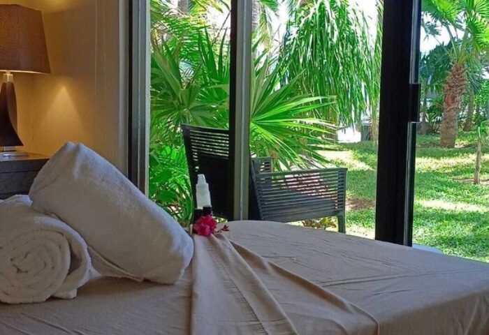 Sina Suites gay-friendly hotel room with rolled towels, lamp, and tropical garden view. Ideal for gay men travel. Relaxing vacation vibes.