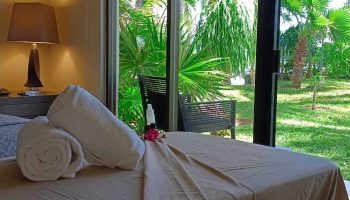Sina Suites gay-friendly hotel room with rolled towels, lamp, and tropical garden view. Ideal for gay men travel. Relaxing vacation vibes.
