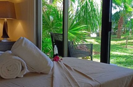 Sina Suites gay-friendly hotel room with rolled towels, lamp, and tropical garden view. Ideal for gay men travel. Relaxing vacation vibes.