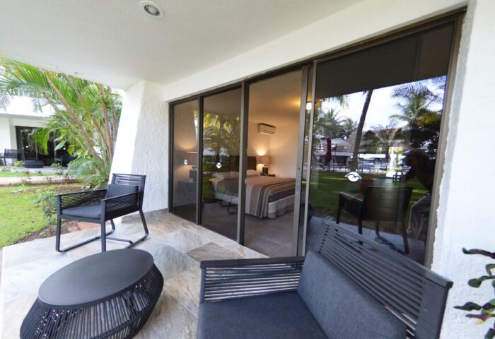 Sina Suites gay-friendly hotel room with patio. Sliding glass doors open to a view of the bedroom and lush tropical grounds. Outdoor seating.