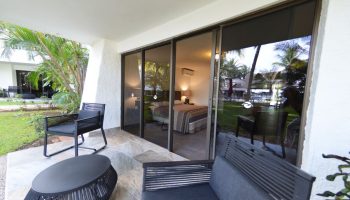 Sina Suites gay-friendly hotel room with patio. Sliding glass doors open to a view of the bedroom and lush tropical grounds. Outdoor seating.