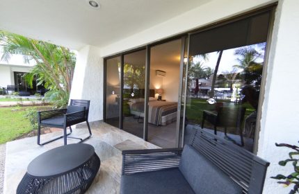 Sina Suites gay-friendly hotel room with patio. Sliding glass doors open to a view of the bedroom and lush tropical grounds. Outdoor seating.