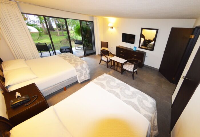 Sina Suites gay-friendly hotel room. Two beds, patio access, TV, and seating area. A comfortable space for gay travelers to relax.