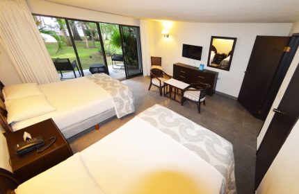 Sina Suites gay-friendly hotel room. Two beds, patio access, TV, and seating area. A comfortable space for gay travelers to relax.