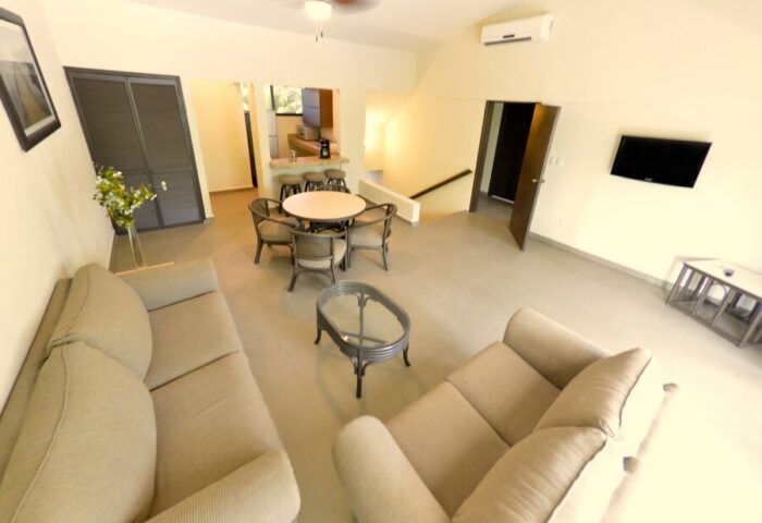 Sina Suites gay-friendly hotel interior. Living area with sofas, dining table, and kitchen bar. Modern design for gay men's travel.