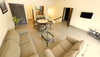 Sina Suites gay-friendly hotel interior. Living area with sofas, dining table, and kitchen bar. Modern design for gay men's travel.