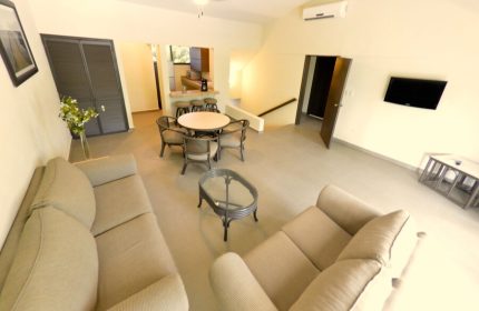 Sina Suites gay-friendly hotel interior. Living area with sofas, dining table, and kitchen bar. Modern design for gay men's travel.