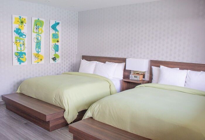 Skylark Hotel gay-friendly room with two beds, wooden headboards, abstract art, and light green bedding. A great option for gay travel.