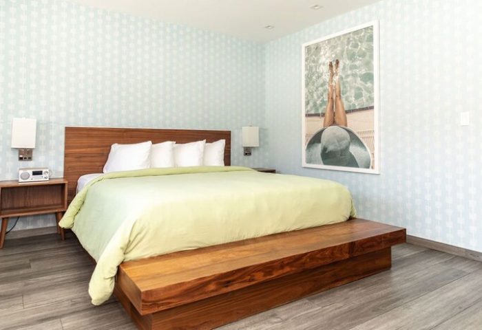 Skylark Hotel bedroom. Gay-friendly hotel room with a king bed, wooden furniture, and a framed photo of a person relaxing by the pool.