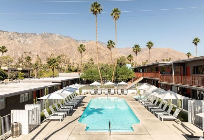 Skylark Hotel pool view. Gay-friendly hotel with mountain backdrop, palm trees, lounge chairs, and umbrellas. Ideal for gay travel.