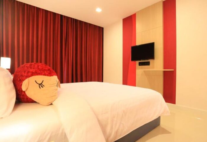 Sleep with Me Hotel Design Hotel at Patong room. Gay-friendly hotel with bed, red curtains, TV, and cute pillow. Patong hotel in Thailand.