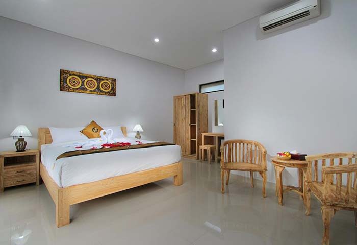 Sleepwell Seminyak gay-friendly hotel room. A bright, modern room with a double bed, wooden furniture, and swan decoration on the bed.