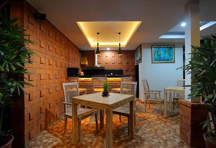 Sleepwell Seminyak gay-friendly hotel dining area. Tables and chairs in a rustic, modern design with brick walls and warm lighting. Bali travel.