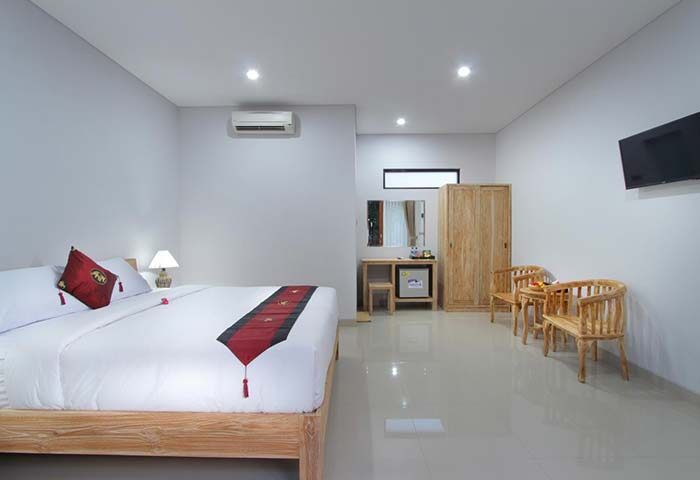Sleepwell Seminyak gay-friendly hotel room. King bed with red accents, wooden furniture, TV, and air conditioning. Modern, clean design.