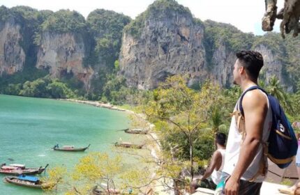 Gay-friendly hotel: Man at The Beach Hostel slumber party, Thailand. Turquoise water, cliffs, and boats. Travel advice for gay men.