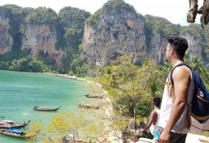 Gay-friendly hotel: Man at The Beach Hostel slumber party, Thailand. Turquoise water, cliffs, and boats. Travel advice for gay men.
