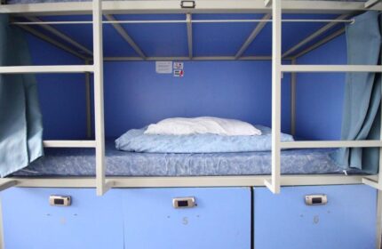 Bunk bed in a gay-friendly Smart Hyde Park Inn Hostel room. Blue interior, lockers below. Comfortable and budget-friendly accommodation.