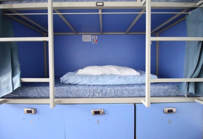 Bunk bed in a gay-friendly Smart Hyde Park Inn Hostel room. Blue interior, lockers below. Comfortable and budget-friendly accommodation.