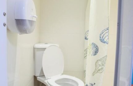 Bathroom at Smart Hyde Park Inn Hostel, a gay-friendly hotel. Toilet, shower curtain with seashell design, and hand towel dispenser.