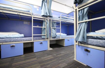 Smart Hyde Park Inn Hostel's gay-friendly dorm. Bunk beds with blue frames, curtains, and storage lockers. A budget-friendly option for gay travelers.