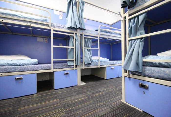 Smart Hyde Park Inn Hostel's gay-friendly dorm. Bunk beds with blue frames, curtains, and storage lockers. A budget-friendly option for gay travelers.