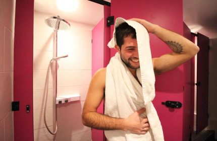 Gay-friendly Smart Hyde Park Inn Hostel shower. Smiling man with towel in pink shower room. Gay travel advice for London hostel.