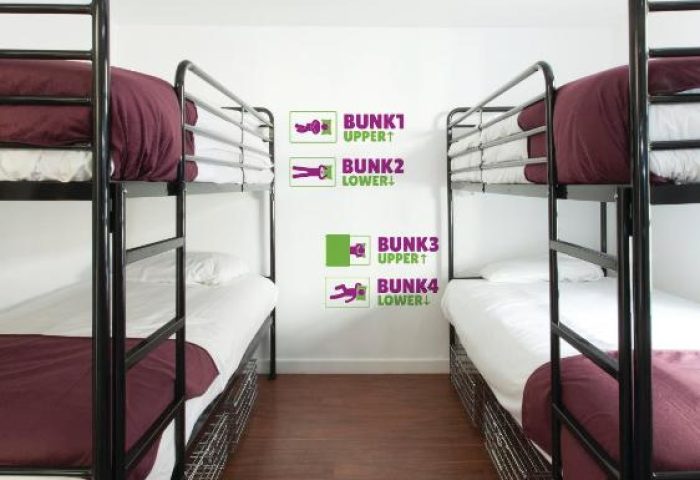 So Hostel gay-friendly hotel room with bunk beds. Modern hostel interior. Bunk bed with maroon blanket. Hostel room with wood floors.