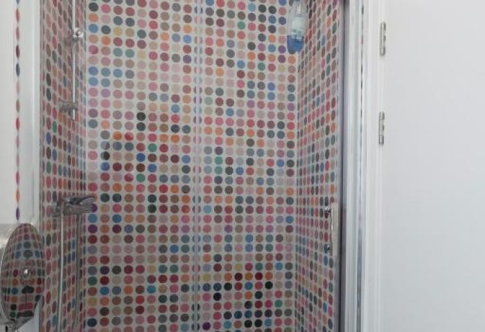 So Hostel gay-friendly hotel shower. Colorful polka dot tiles adorn the shower stall. Modern design for gay travelers. Hostel bathroom.
