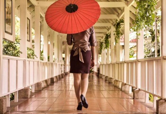 Woman with umbrella at Sofitel Angkor Phokeethra Golf & Spa Resort. Gay-friendly hotel with elegant architecture and relaxing ambiance.