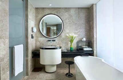 Bathroom at Sofitel Beijing Central, a gay-friendly hotel. Features a round mirror, modern sink, bathtub, and stylish decor. Ideal for gay travel.