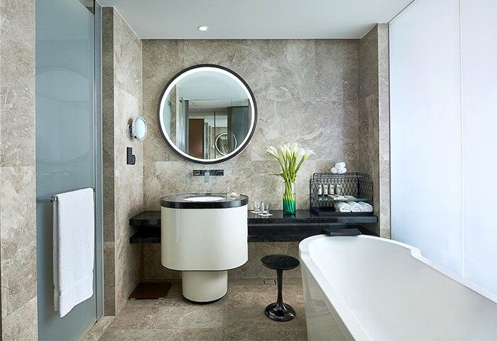 Bathroom at Sofitel Beijing Central, a gay-friendly hotel. Features a round mirror, modern sink, bathtub, and stylish decor. Ideal for gay travel.